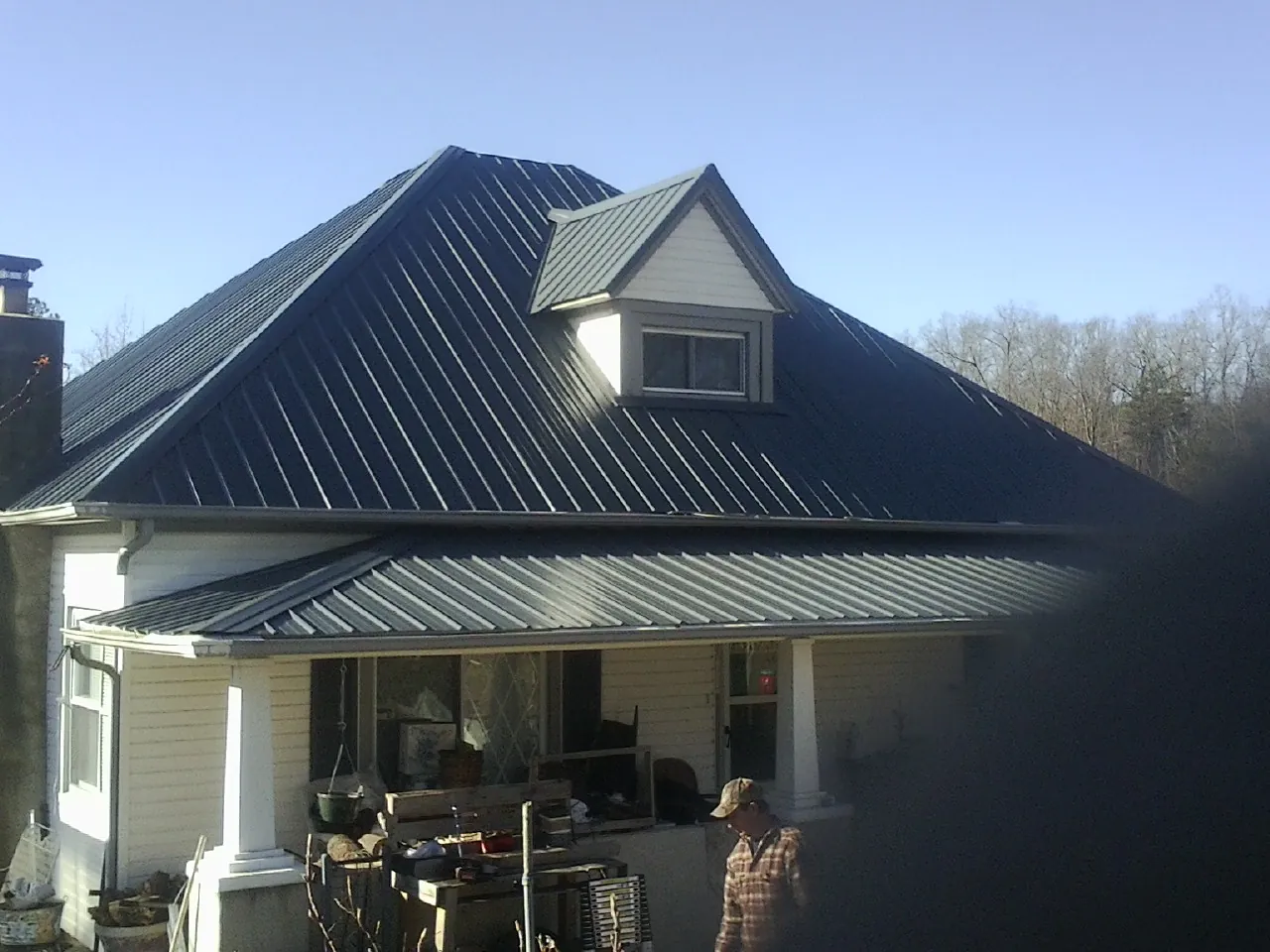 Dark blue standing seam metal roof with a dormer above a front porch in Alburtis