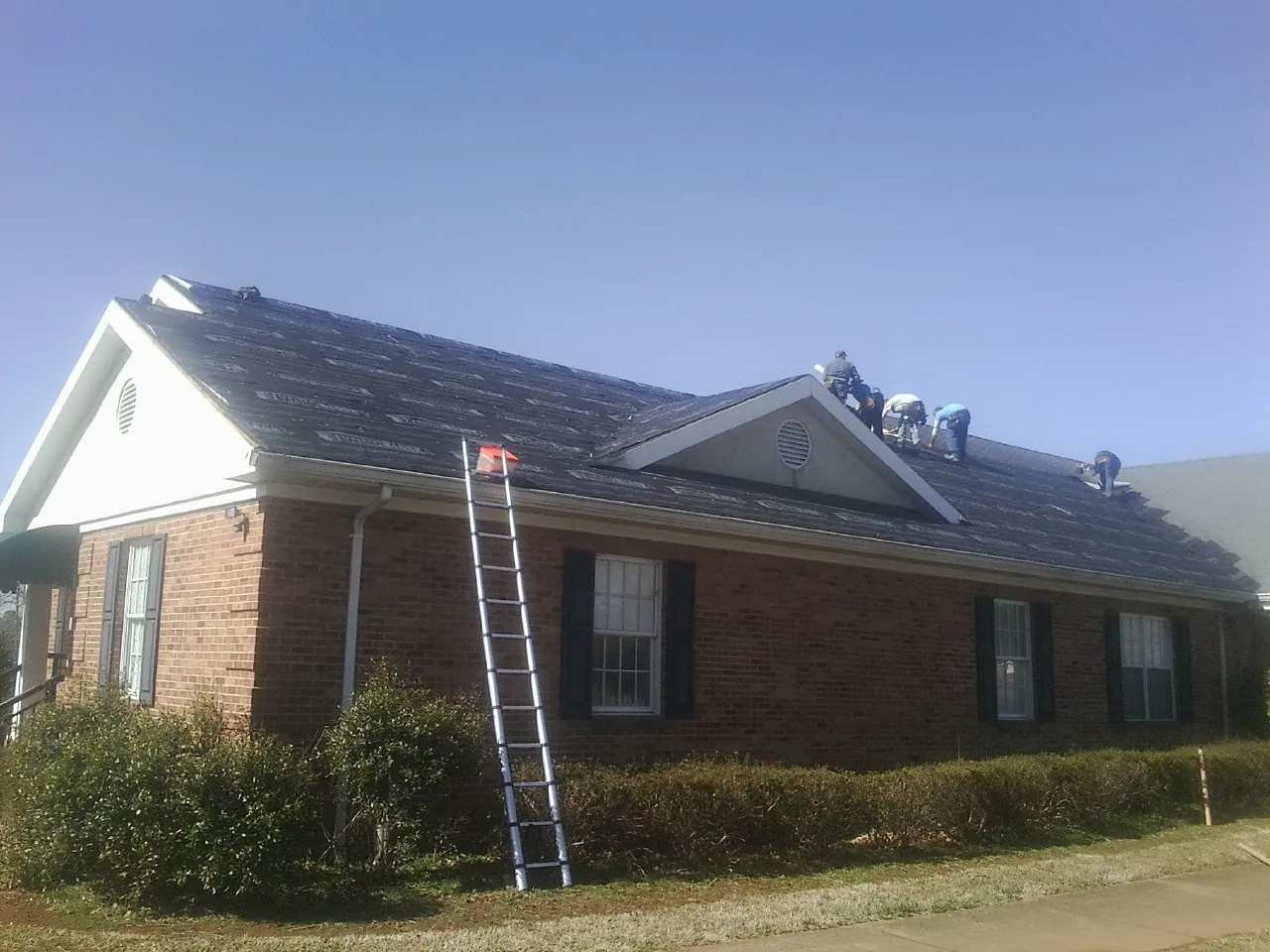 Crew tearing shingles off a brick ranch roof with a ladder set — Emergency Roof Repair work by our crew in Alburtis