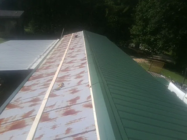 Old rusted panels beside newly installed green metal roofing — Wind Damage Roof Repair by Roofing Brothers in Alburtis