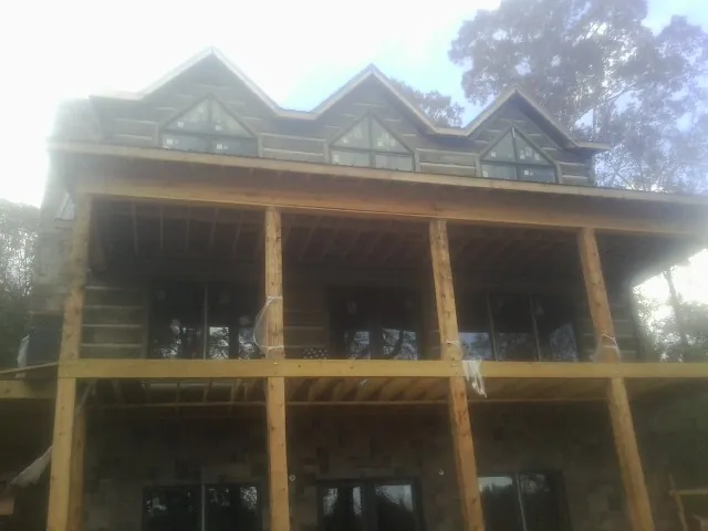 Dormers and porch framing on a large log home under construction — Roof Coating work by our crew in Alburtis