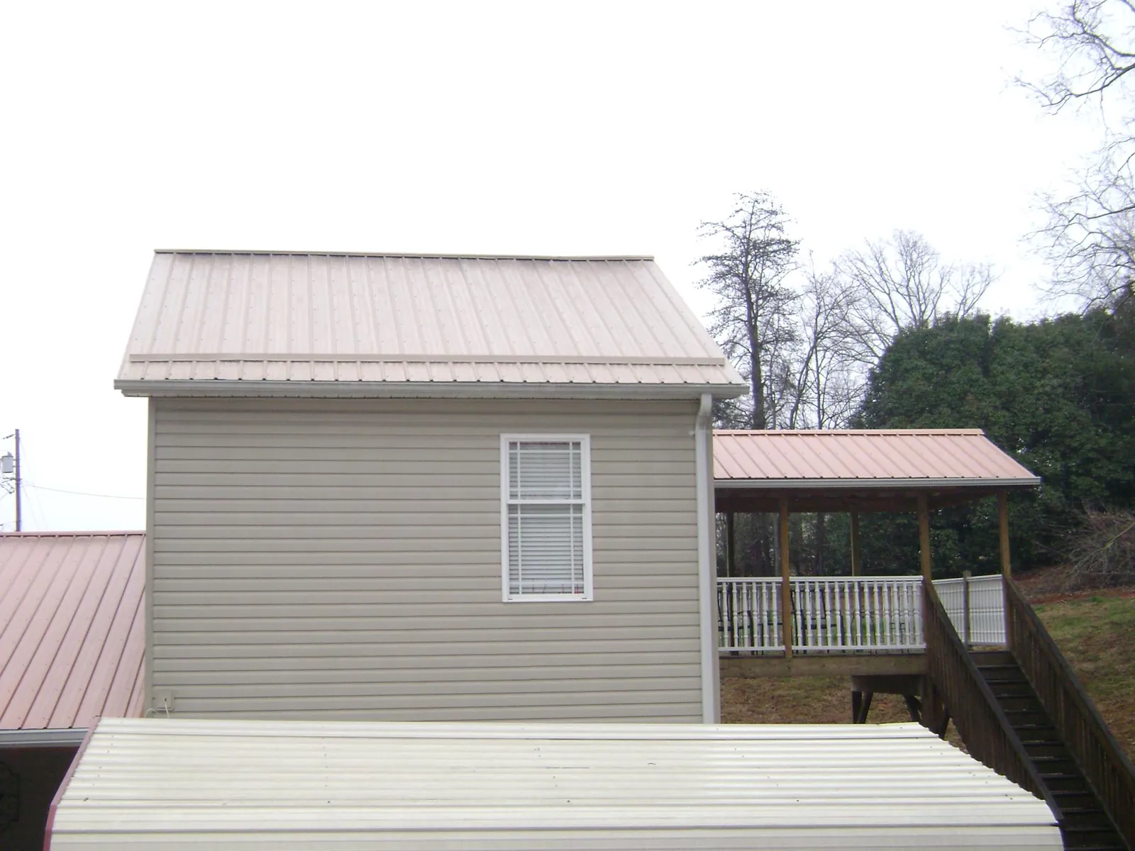 Tan metal roofs on a two story addition and attached porch, from a Roof Replacement job in Alburtis
