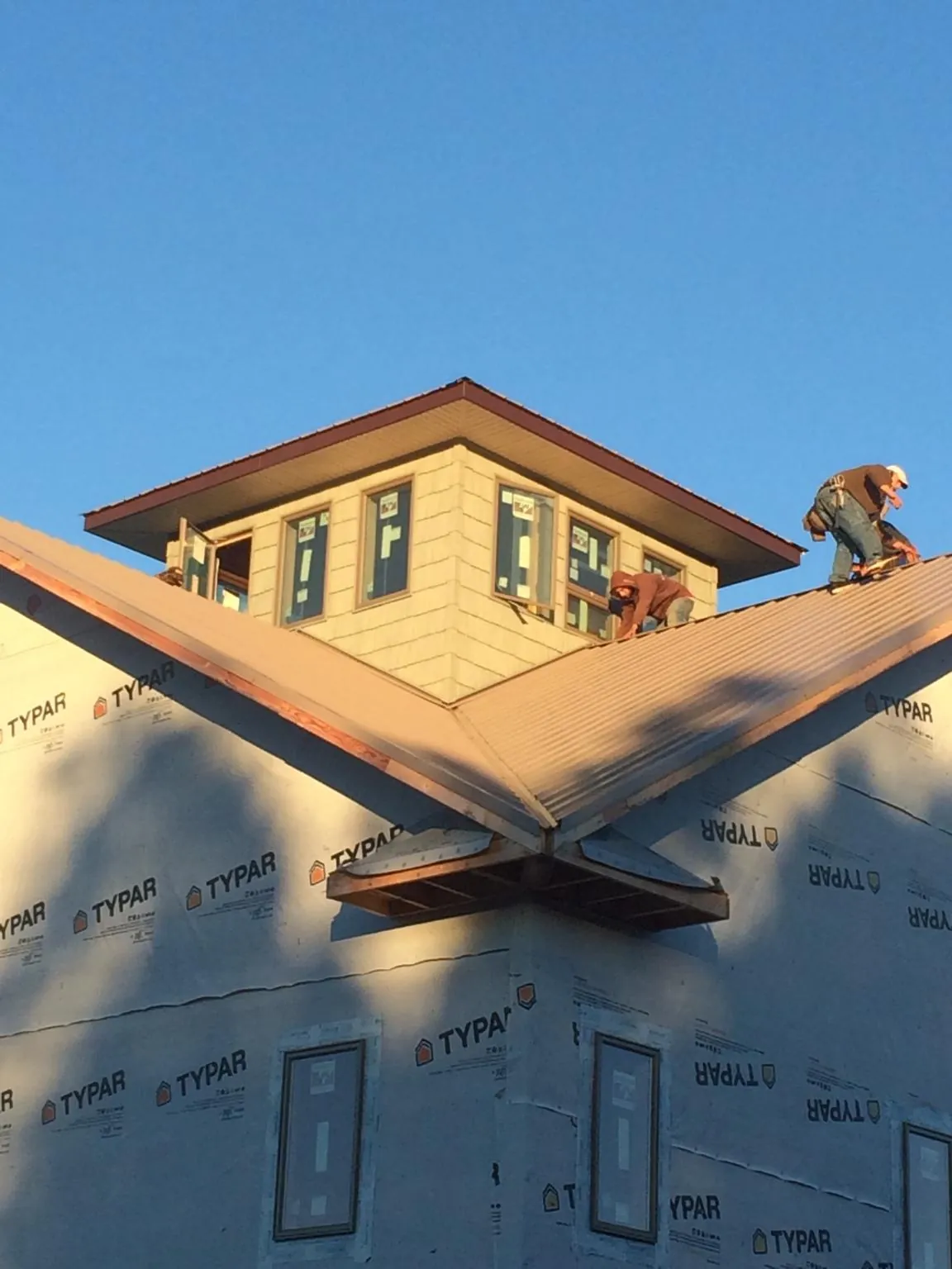 Roofers working around a rooftop cupola on a new metal roof at sunset — Roof Waterproofing in Alburtis by Roofing Brothers